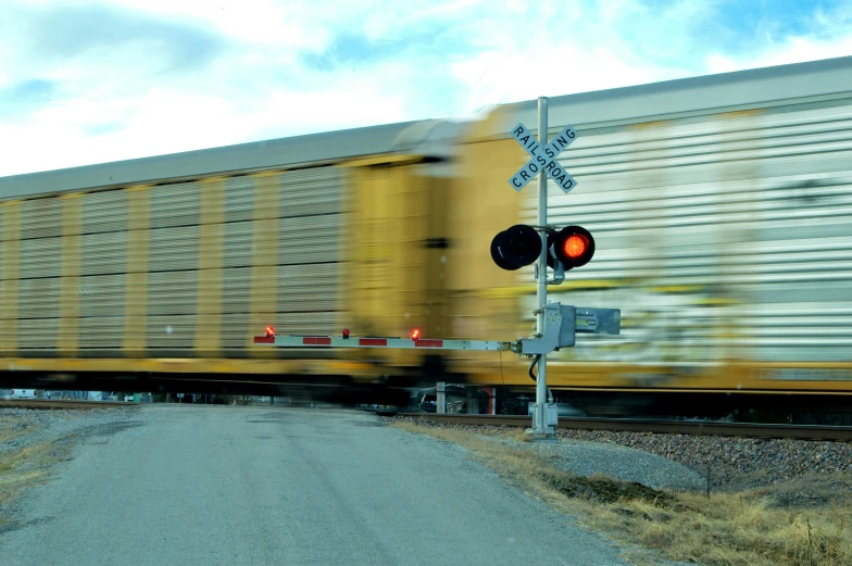 a yellow train speeding past a red traffic light