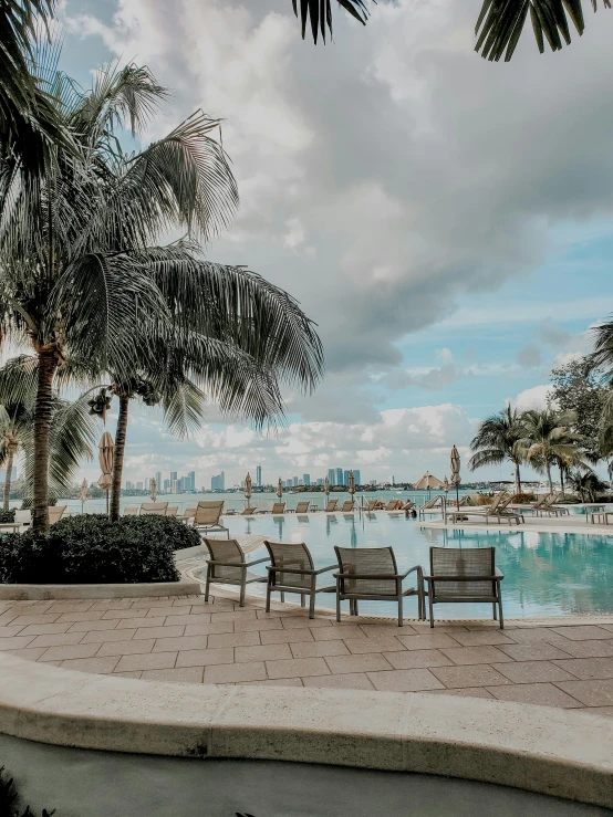 a pool filled with chairs surrounded by palm trees