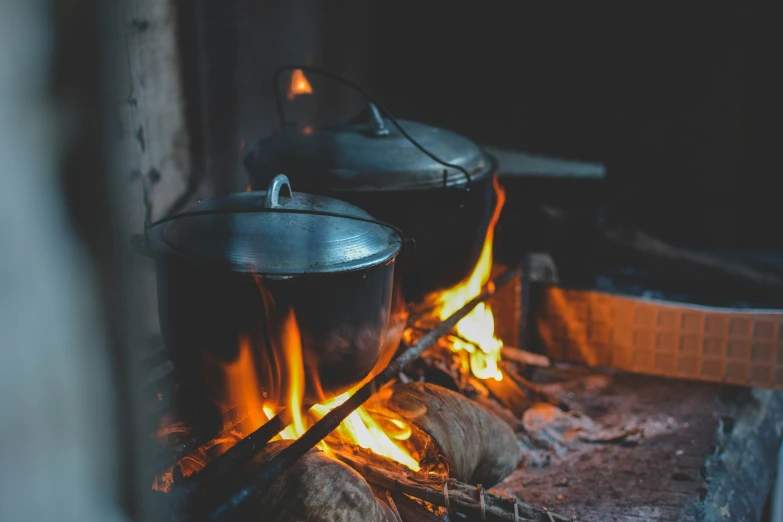 two pot on top of a fire with flames in the background