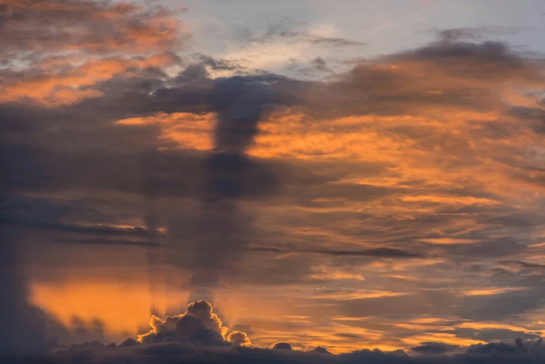 a jet flying into the distance with a huge cloud in the sky