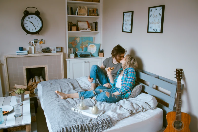 a couple kissing on their bed as they eat breakfast