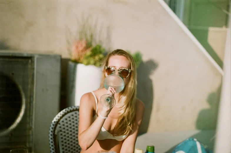 a woman with sunglasses and a towel around her neck brushing her teeth