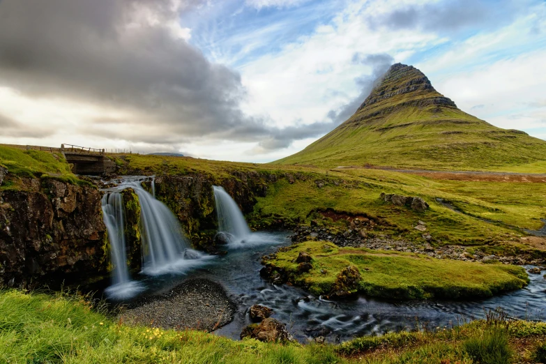 a waterfall with a bridge at the foot