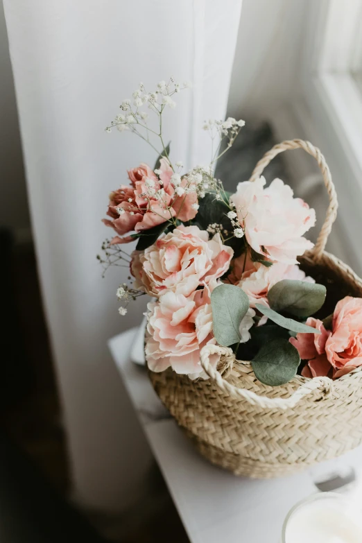 a basket containing flowers on a table near a window