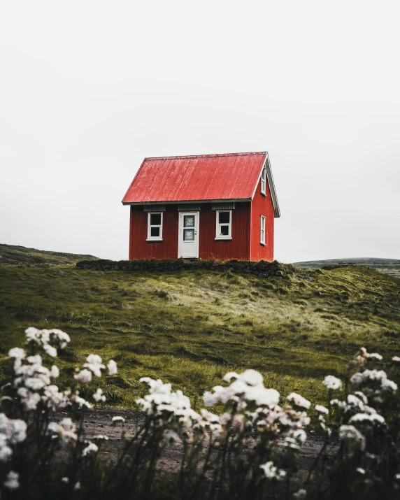 a small red cabin sitting on the side of a hill