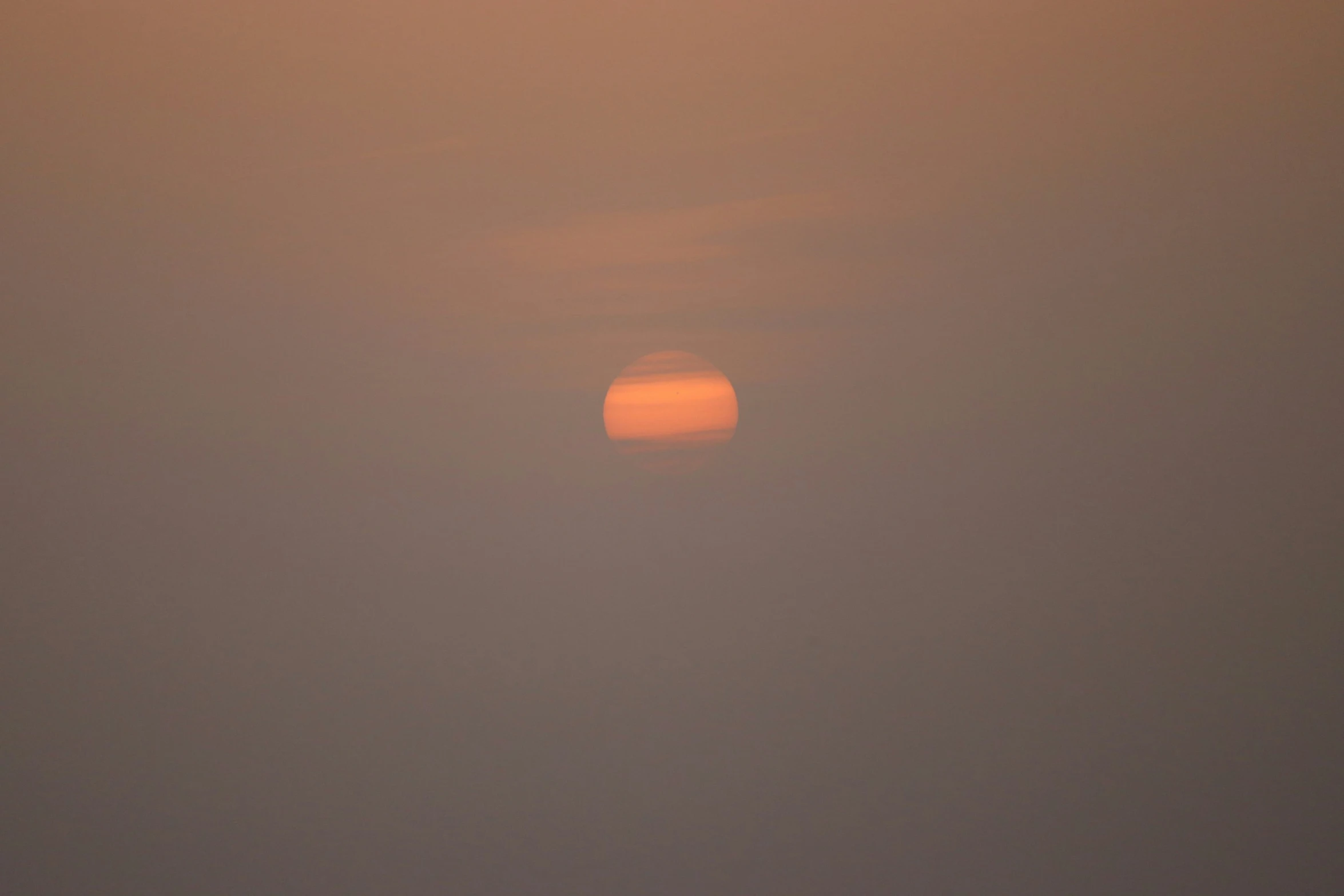 the sun is rising behind a foggy hazy sky