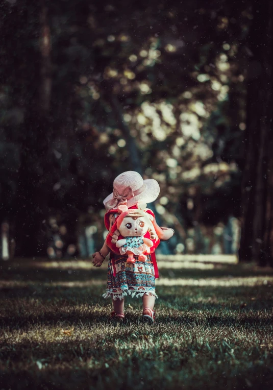 a child carrying a stuffed animal in front of trees