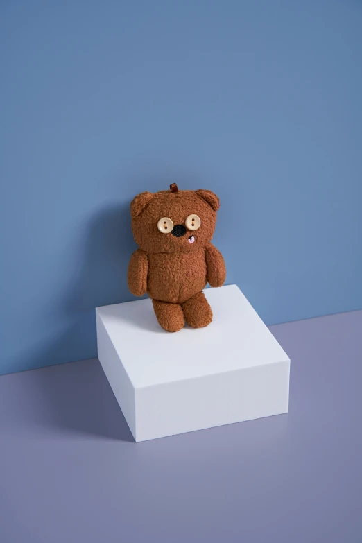 a teddy bear sits on a white block
