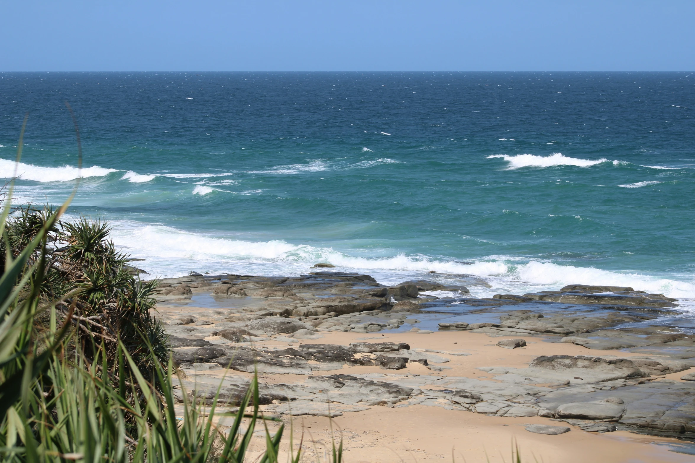 an ocean beach is lined with large rocks