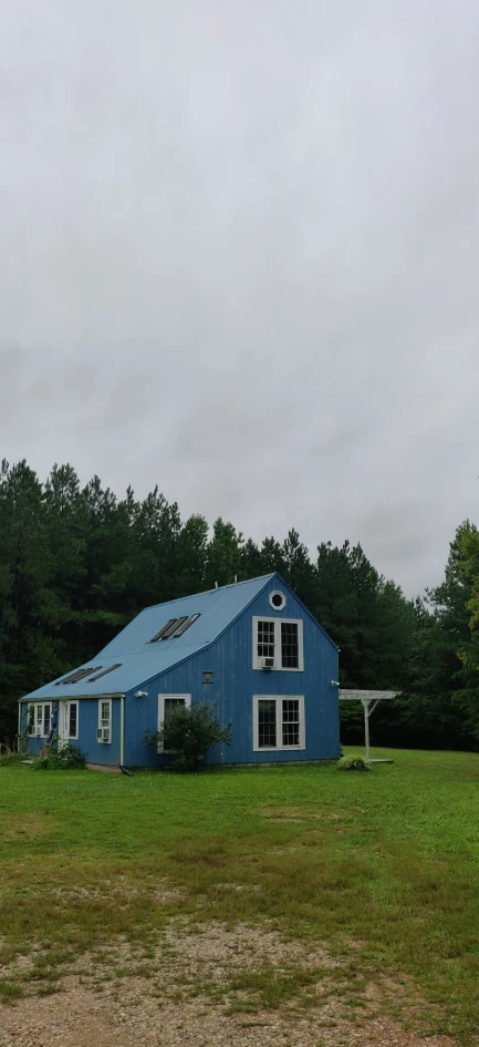 a blue barn with an awning over it sitting next to a white gazebo