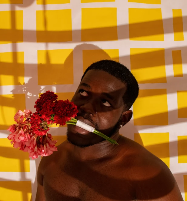 the man has been painted with a flower and is holding a paper strip around his neck