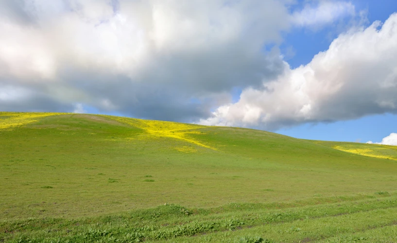 a large hill covered in grass and clouds