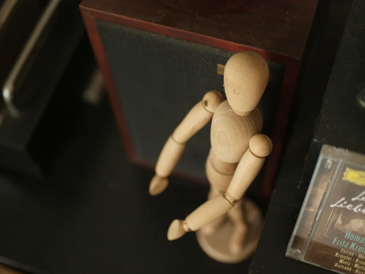 a wooden doll sits next to a cd player