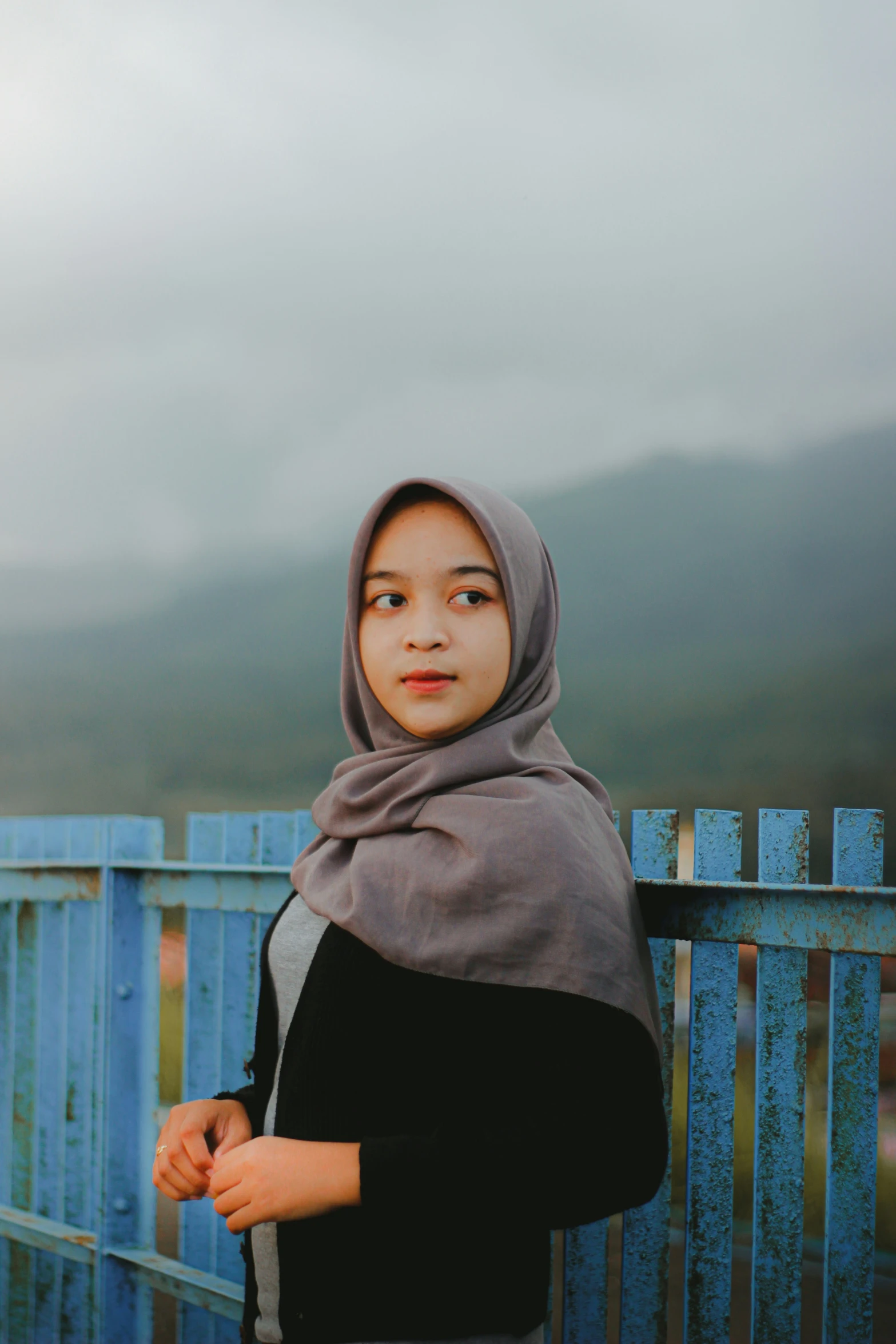 the young woman is leaning on a metal rail