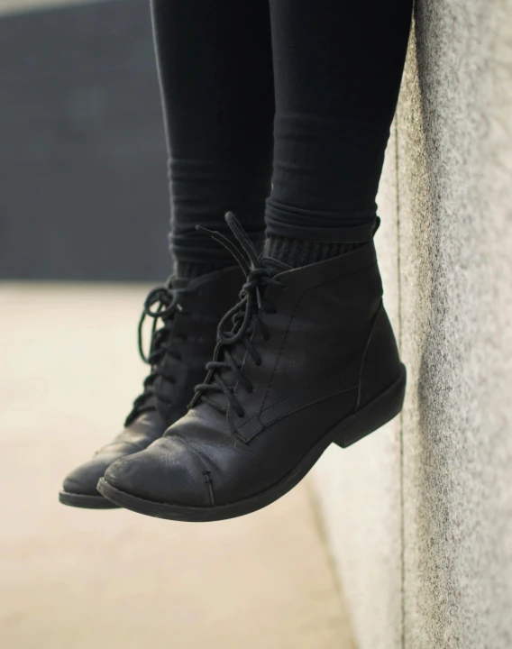 the legs of a woman standing on top of a cement wall