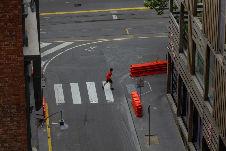 an empty street next to buildings with construction workers walking on the sidewalk