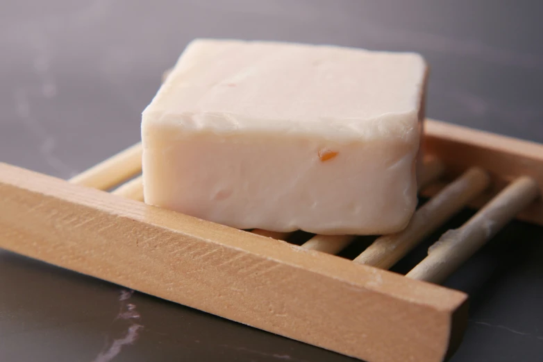 a block of goat milk is sitting in a wooden dish