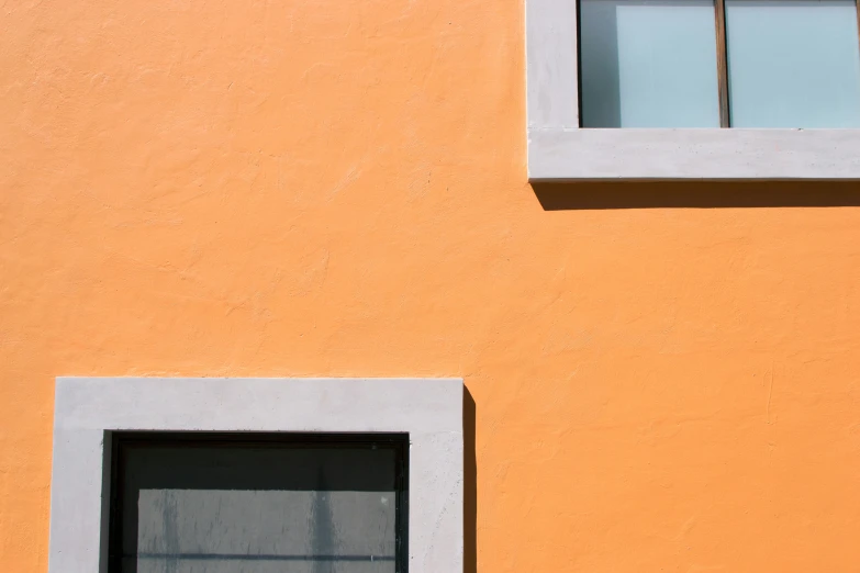 a cat sitting on the side of an orange building