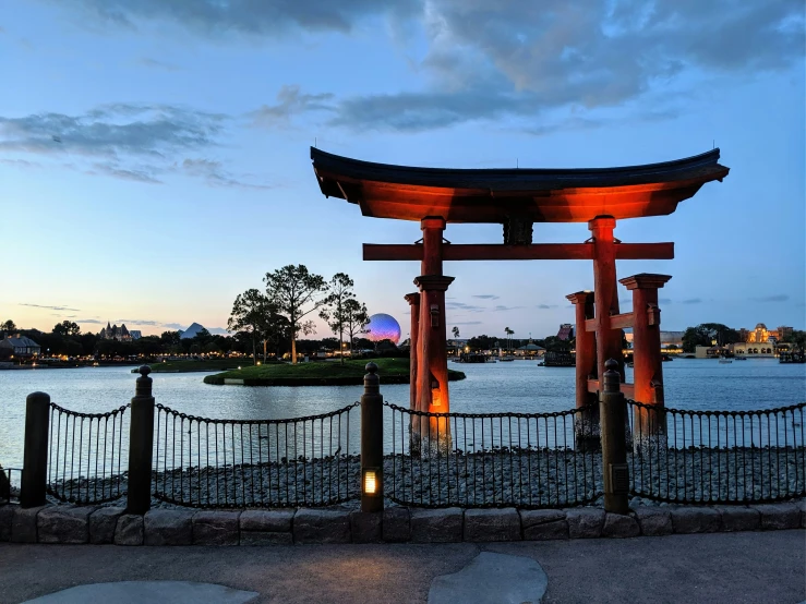 an asian gate by the water in front of a blue sky