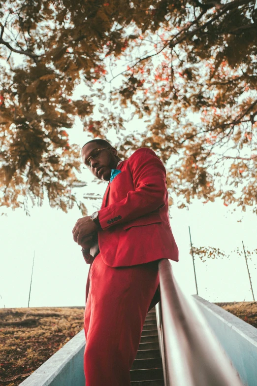 a black man wearing red clothes is leaning on the edge of stairs