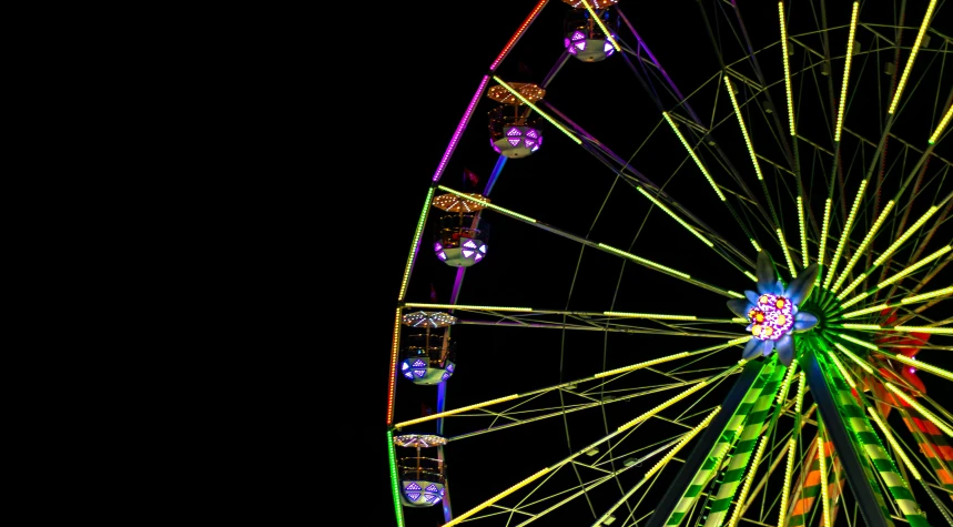 a colorful ferris wheel lit up on a dark night