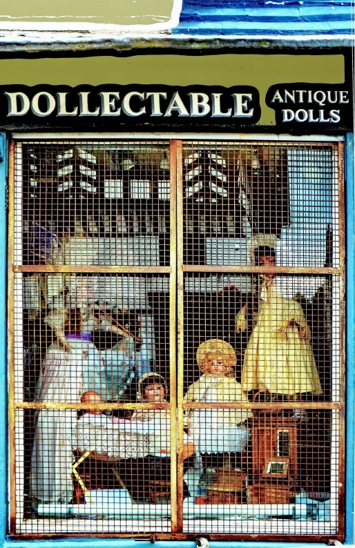 three people inside a cage that is filled with dolls