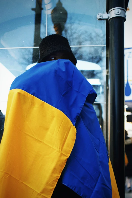 a person standing on the bus while a blue and yellow blanket covers him