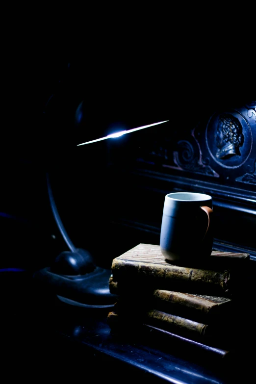 a mug sitting on top of some books in the dark