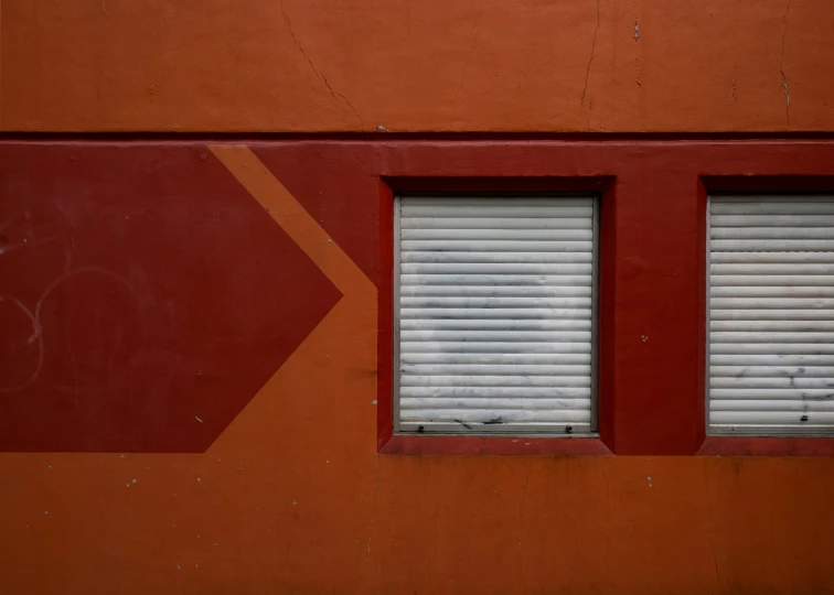 a red wall with three different shutters and two windows