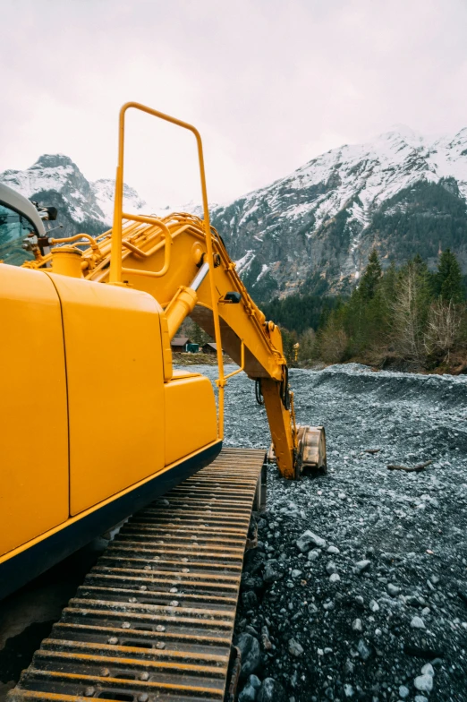 a yellow truck with it's front end extended and there is some rocks below