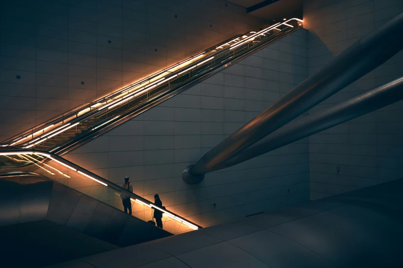 people moving down an escalator at night