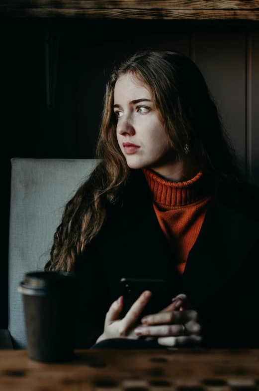 a woman sitting at a table using a cell phone