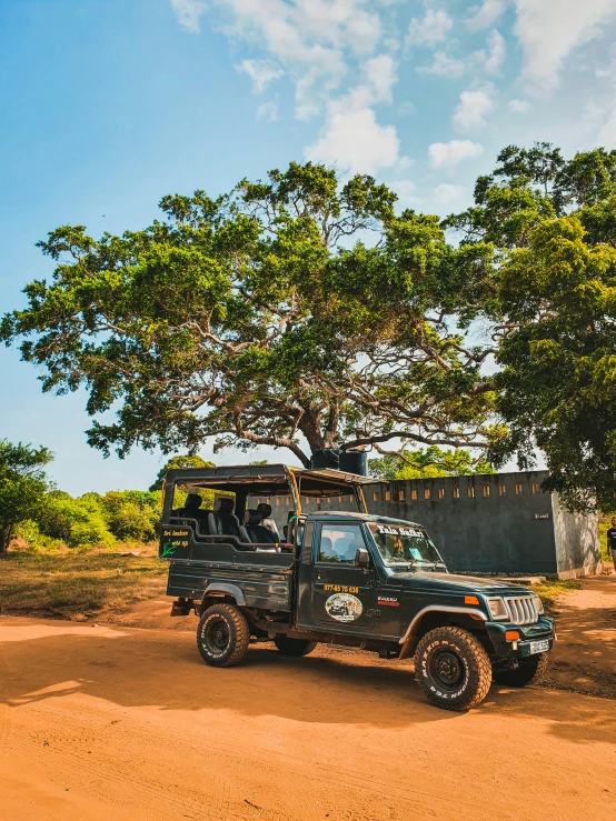 a jeep with the roof top down, sitting in a dirt road next to trees