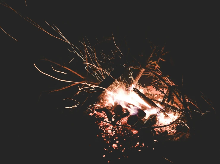 a fire burning on a dark background with lots of small nches
