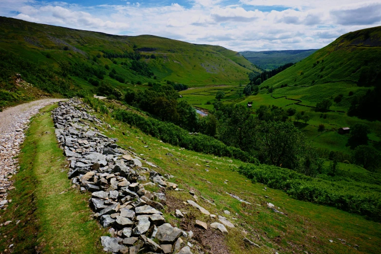 rocks and grass lined path in green hilly valley