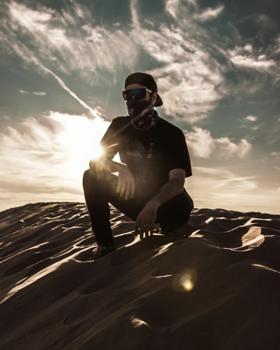 a man sitting on top of a sandy beach under a sun