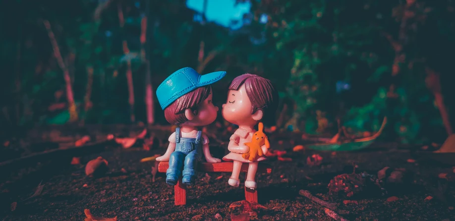 two little toy people sitting on small stools