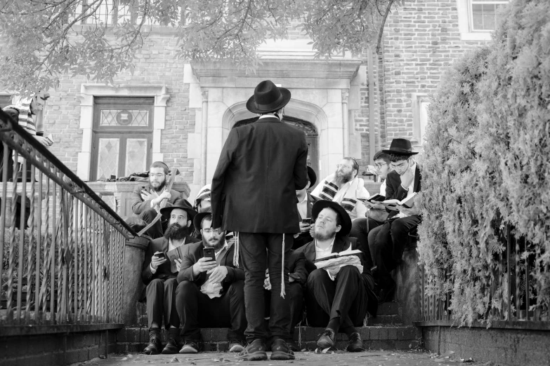 people are sitting down near a building while the man in black speaks