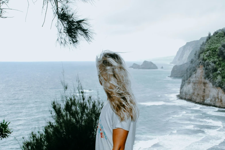 the back view of a woman with long hair and looking at water