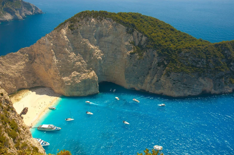 two large boulders sit on top of the ocean near a beach with many boats