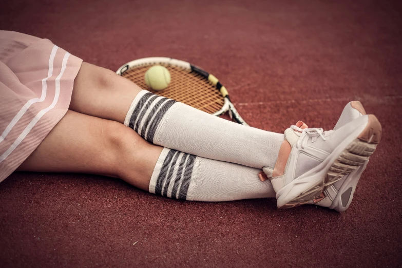 a person sitting down with tennis rackets and balls in the ground