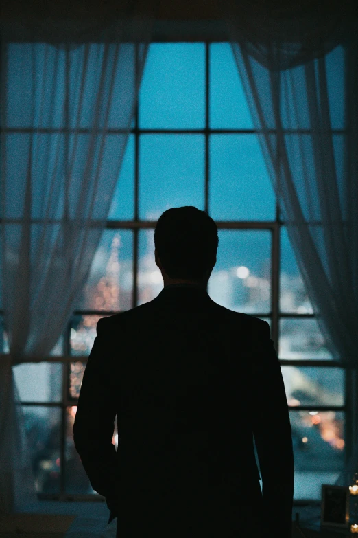 a man in a dark room looking out a window