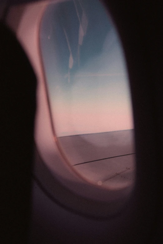 an airplane wing in the sky viewed through a window