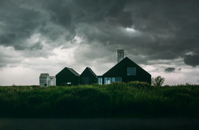 three houses are standing on a grassy hillside