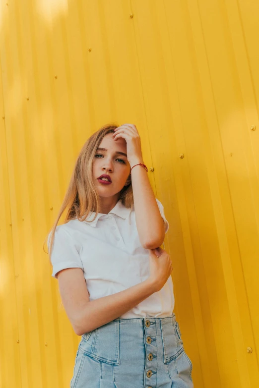 a woman posing for the camera near a yellow wall