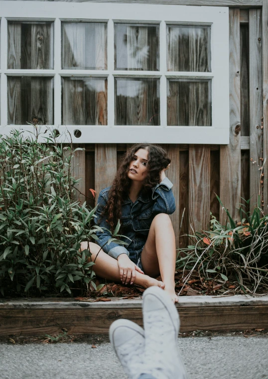 a young woman sitting on the ground with her feet up