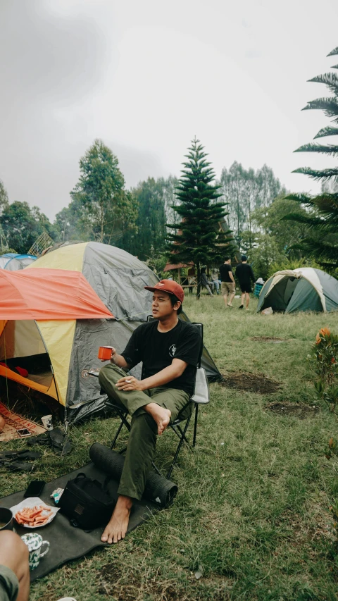 man sitting in chair with camping equipment around him