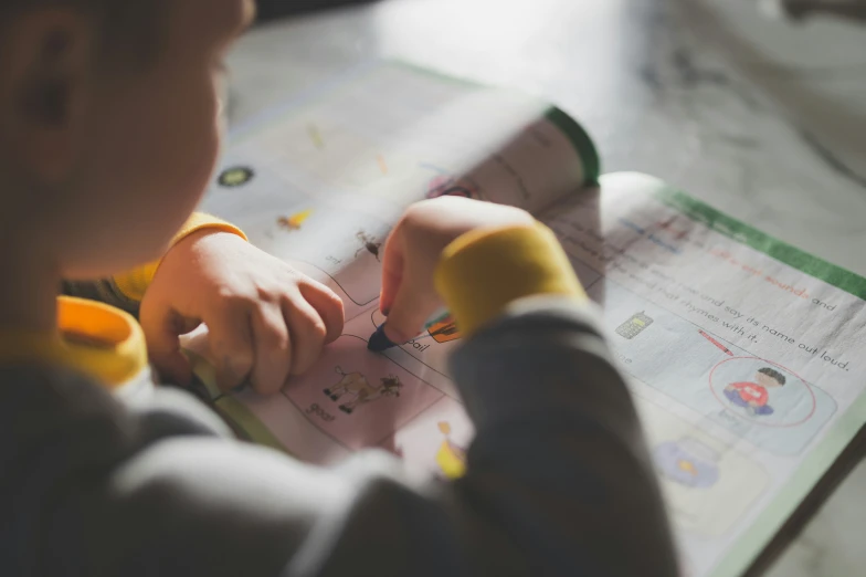 a child holding a pen and looking at a small book