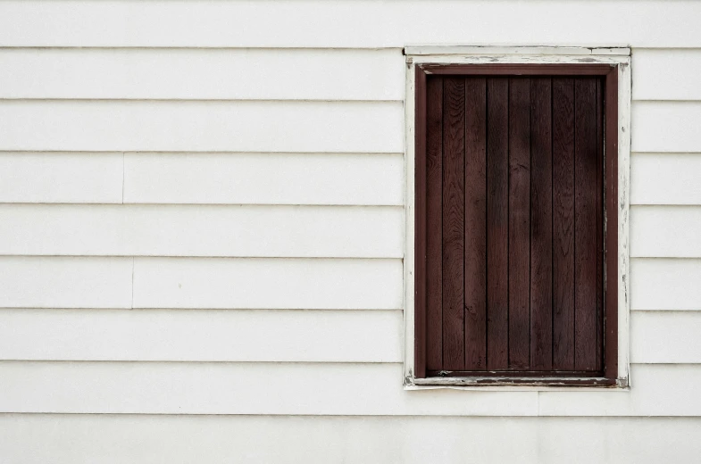 the side of an older house with a window that is closed