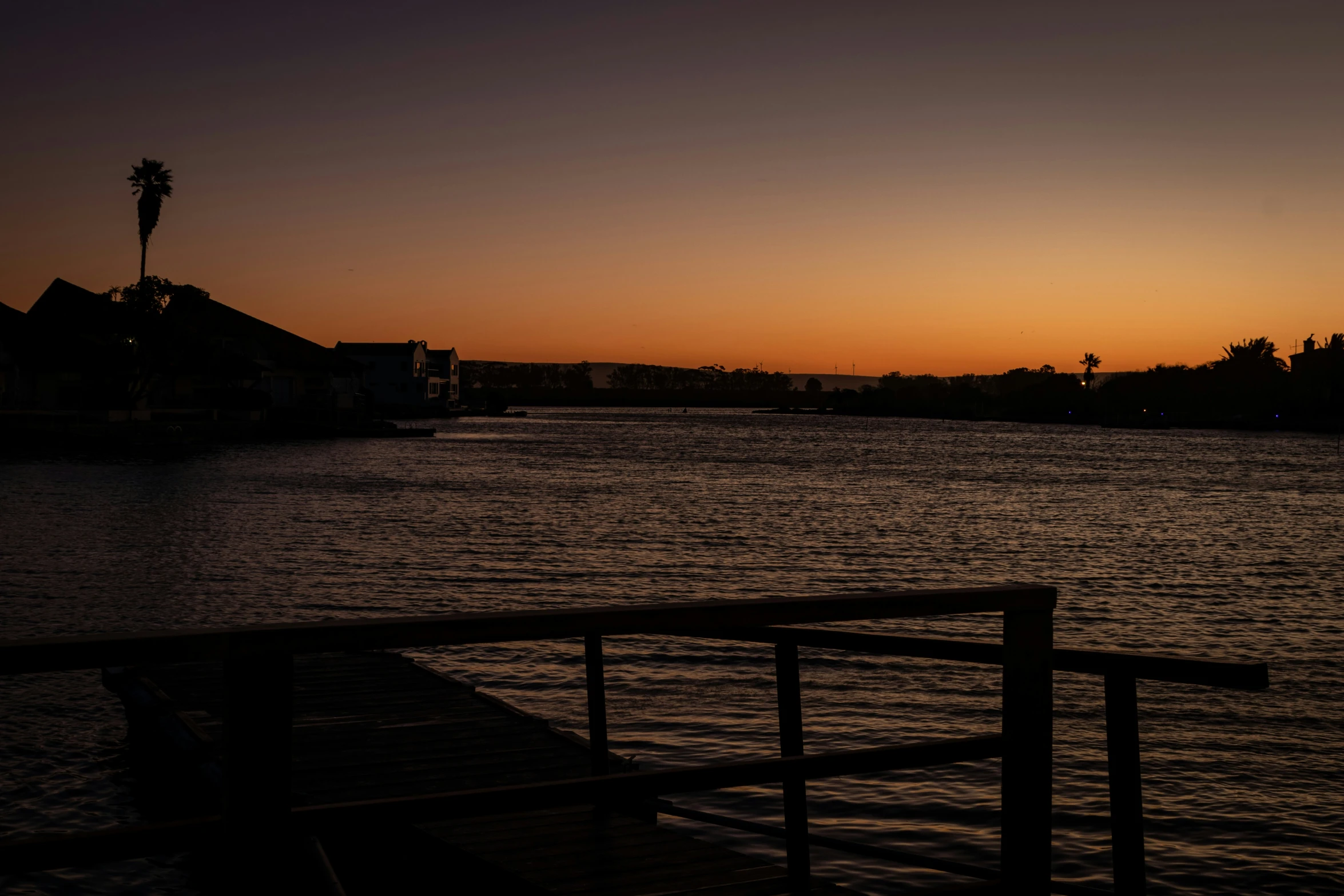 a sunset behind a boat dock with palm trees in the distance